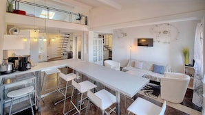 A modern kitchen with a central island, bar stools, and a dining area. - Upstays Port View 88m² Apartment Suquet (Cannes)