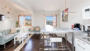A modern kitchen with a dining area, large windows, and a view of the city. - Upstays Port View 88m² Apartment Suquet (Cannes)