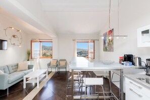 A modern kitchen with a dining area, large windows, and a view of the city.