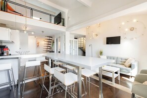 A modern kitchen with a central island, bar stools, and a dining table.