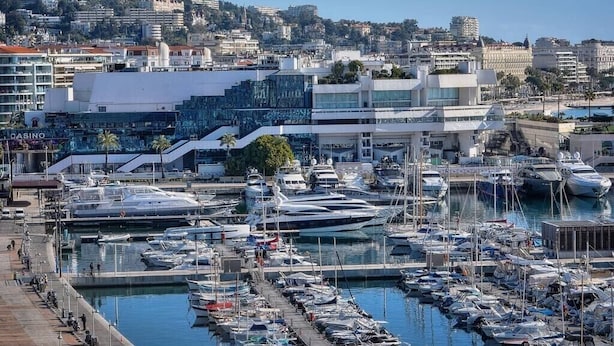 A marina with numerous boats docked, a casino building, and a cityscape in the background. - Upstays Port View 88m² Apartment Suquet (Cannes)