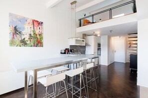 Uma cozinha moderna com área de bar, um quadro na parede e uma escada para um andar superior.