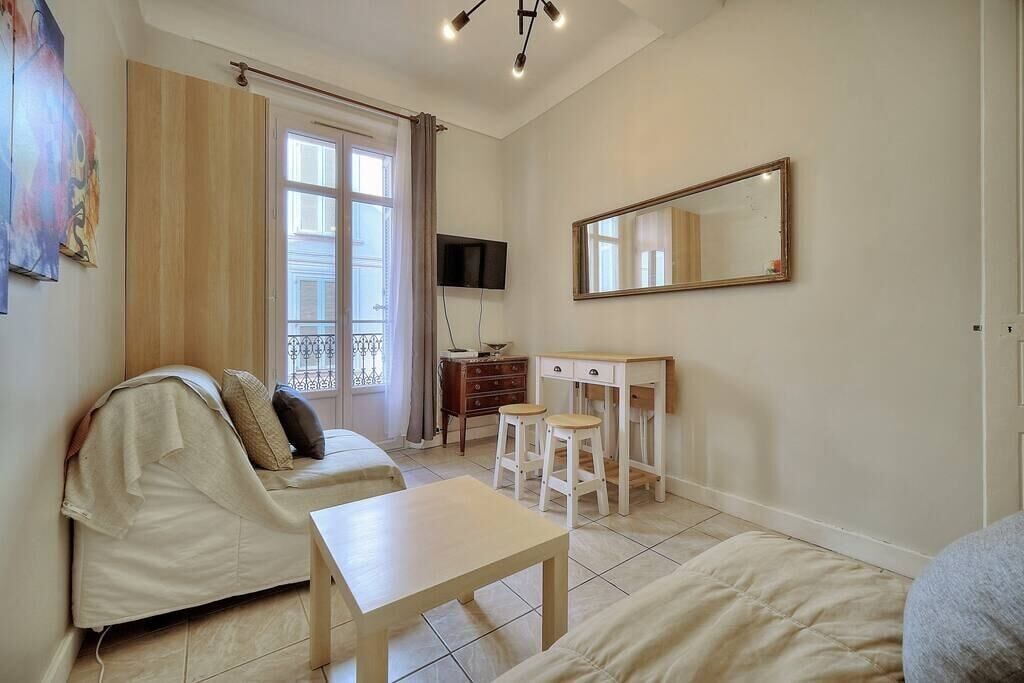A room with a bed, a small table, a TV, and a mirror.