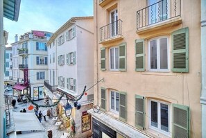 Une rue étroite bordée d’immeubles à l’architecture traditionnelle, avec des volets et des balcons.