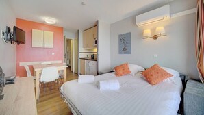 A hotel room with a bed, a desk, a chair, a kitchenette, and a television. - Upstays Terrace 30m² Apartment Croix des Gardes (Cannes)