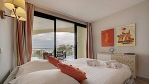 A hotel room with a large bed, a balcony with curtains, and two posters on the wall. - Upstays Terrace 30m² Apartment Croix des Gardes (Cannes)