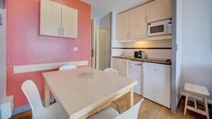 A compact kitchen with a microwave, coffee maker, and dishwasher. There is a small dining area with a table and chairs. - Upstays Terrace 30m² Apartment Croix des Gardes (Cannes)