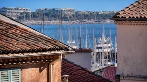 A coastal view with a marina, buildings in the background, and a tiled roof in the foreground. - Upstays cosy 20m² Apartment Suquet (Cannes)