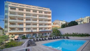 A modern apartment building with a rooftop swimming pool, multiple balconies, and a wooden deck with lounge chairs. - Immogroom - Charming apartment - Close to beaches (Cannes)