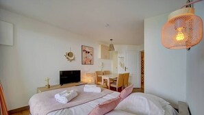 A hotel room with a bed, a desk, a chair, a television, and a hanging light fixture. - Upstays Terrace Pool 37m² Apartment (Cannes)