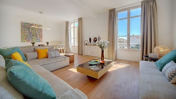 A modern living room with a sofa, coffee table, and large windows offering a city view.