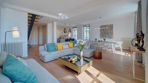 A spacious living area with a sofa, coffee table, and a dining table with chairs.