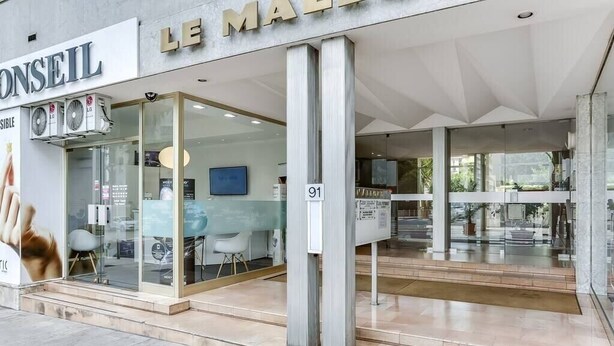 Un edificio moderno con fachada de vidrio, un letrero que dice “LE MAIRE” y el número “91” que indica su ubicación.