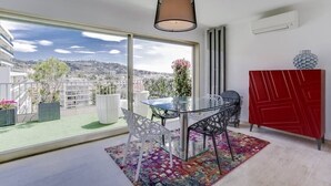 Un balcón moderno con una mesa de vidrio, sillas y una alfombra colorida.