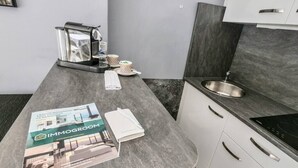 Een moderne keuken met een marmeren aanrechtblad, een ingebouwde kookplaat en een roestvrijstalen spoelbak.