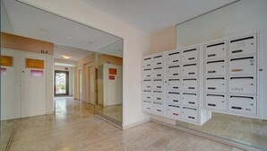 A hallway with a mirrored wall and a row of white mailboxes on the right. - Upstays Terrace 25m² Studio Carnot (Cannes)