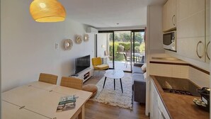 A modern kitchen with a dining area, a TV, and a large window. - Upstays Garden Terrace Pool 30m² Apartment (Cannes)