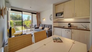 A modern kitchen with a microwave, sink, and cabinets. There is a dining area with a table and chairs. - Upstays Garden Terrace Pool 30m² Apartment (Cannes)