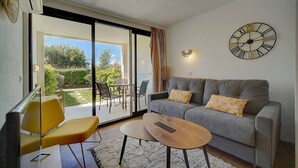 A modern living room with a grey sofa, yellow armchair, and a round coffee table. - Upstays Garden Terrace Pool 30m² Apartment (Cannes)
