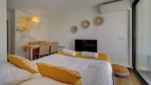 A hotel room with a bed, a desk with chairs, a television, and a large window. - Upstays Garden Terrace Pool 30m² Apartment (Cannes)