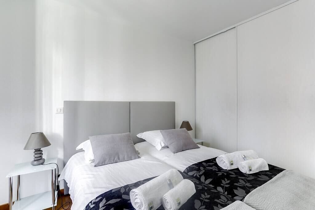 A modern hotel room with a large bed, two bedside tables, and a nightstand.