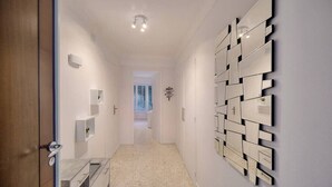 Un couloir au design moderne, agrémenté d’un miroir mural et d’un luminaire.