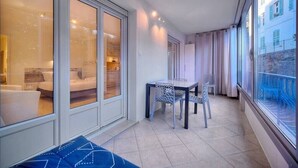 Un balcon doté d’un espace repas, d’un canapé et offrant une vue sur un immeuble également pourvu de balcons.