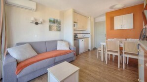 A compact living space with a sofa, dining table, and kitchenette.