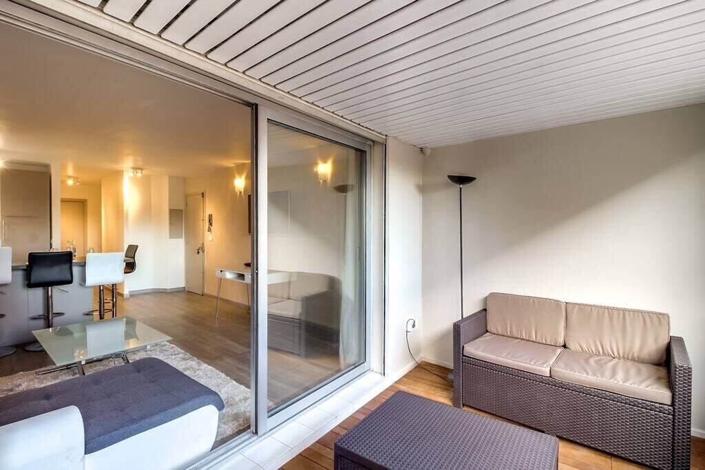 A modern living room with a glass sliding door leading to a dining area, a sofa, and a coffee table.