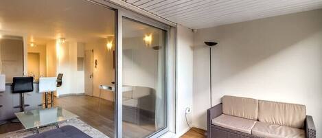 A modern living room with a glass sliding door leading to a dining area, a sofa, and a coffee table.