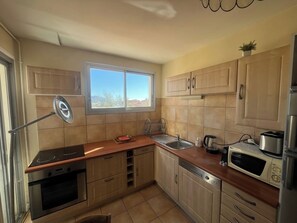 Una cocina compacta con ventana, estufa, fregadero, microondas y armarios de madera.