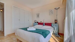 A bedroom with a bed, a wardrobe, a floor lamp, and a painting on the wall. - Upstays Sea View Terrace 60m² Apartment (Cannes)