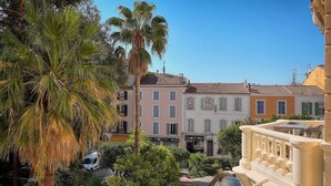 A courtyard with a palm tree, a fountain, and buildings with balconies.
