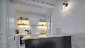 Una cocina moderna con armarios blancos, encimera de madera y horno integrado.