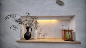 Una estantería con un florero negro, floreros blancos y un farol.