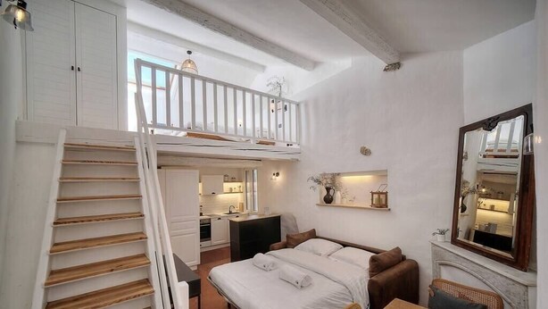Un dormitorio con cama en literas, una mesa de comedor, chimenea y zona de cocina.