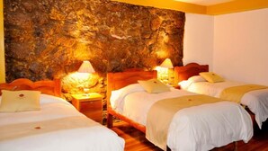 Habitación de hotel con dos camas, cabeceros de madera y una pared texturizada grande detrás de las camas.