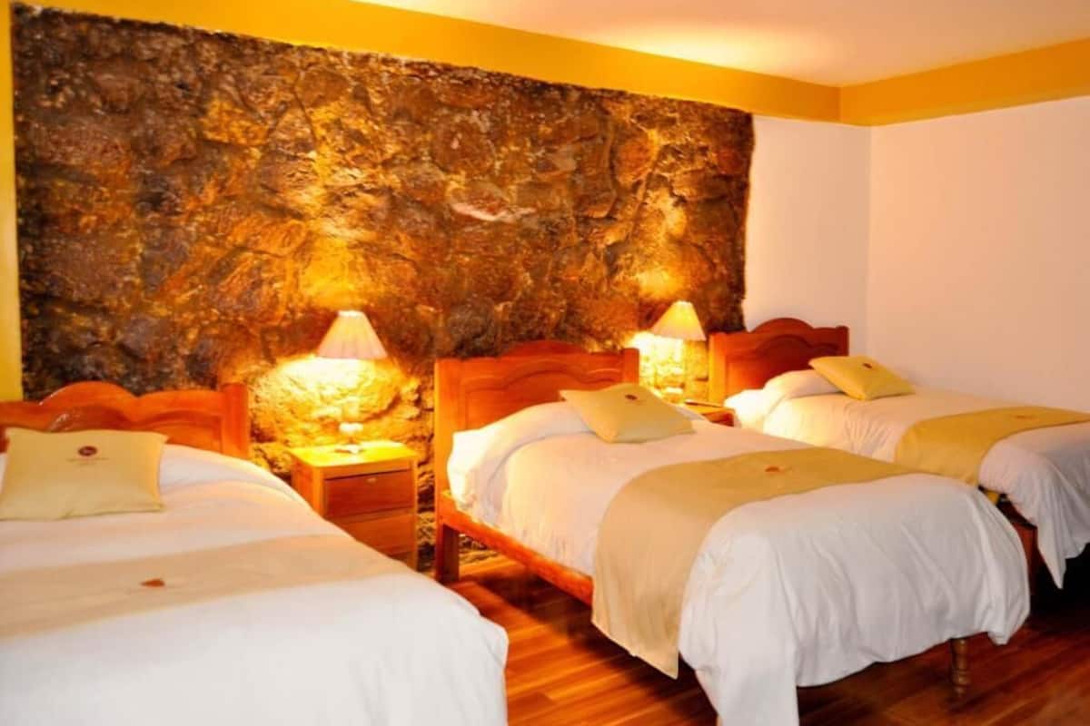 Ein Hotelzimmer mit zwei Betten, Holz-Kopfteilen und einer großen, strukturierten Wand hinter den Betten.
