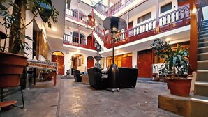 Un vestíbulo amplio con techo alto, varios balcones y una zona de estar central con sofás y una mesa.