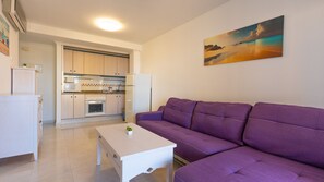 A modern living room with a purple sofa, a white coffee table, and a kitchen in the background. - 13C Turquesa Beach con Vistas al mar (Calp)