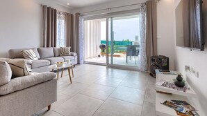 A modern living room with a grey sofa, a coffee table, and a TV mounted on the wall. - Vacation home Romeo by Interhome (Pula/Vodnjan)