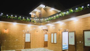 A hotel room with a large bed, a small table, and a balcony with plants. - Doi Thong Homestay (Ha Giang 1)