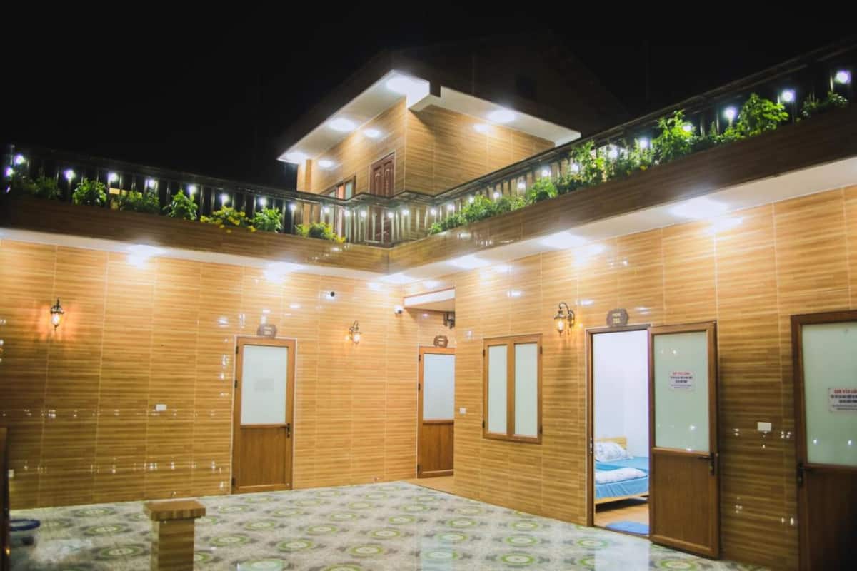 A hotel room with a large bed, a small table, and a balcony with plants.