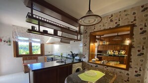 A kitchen with a central island, wooden cabinets, a window with a view, and a patterned wall. - Vivienda Vacacional La Casa Azul ll (Ceceda)