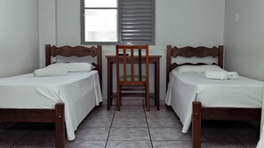 A room with two wooden beds, a small table, and a chair. - Carlton Imbiara Express (Araxá)