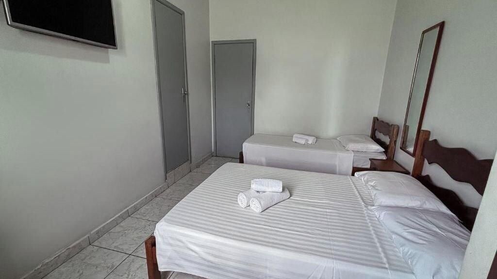 Een hotelkamer met twee bedden, een televisie en een deur.
