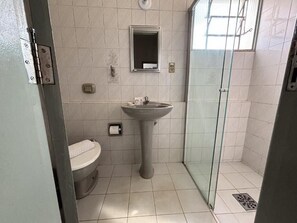 A bathroom with a toilet, sink, and glass shower enclosure. - Carlton Imbiara Express (Araxá)