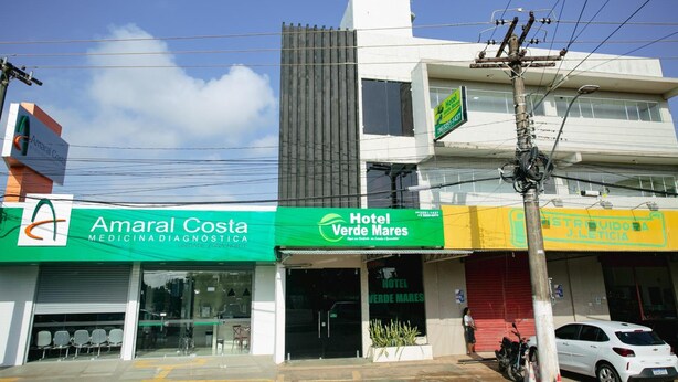 A building with a green sign for Amaral Costa and a yellow sign for Hotel Verde Mares. - Hotel Verde Mares (Macapa)