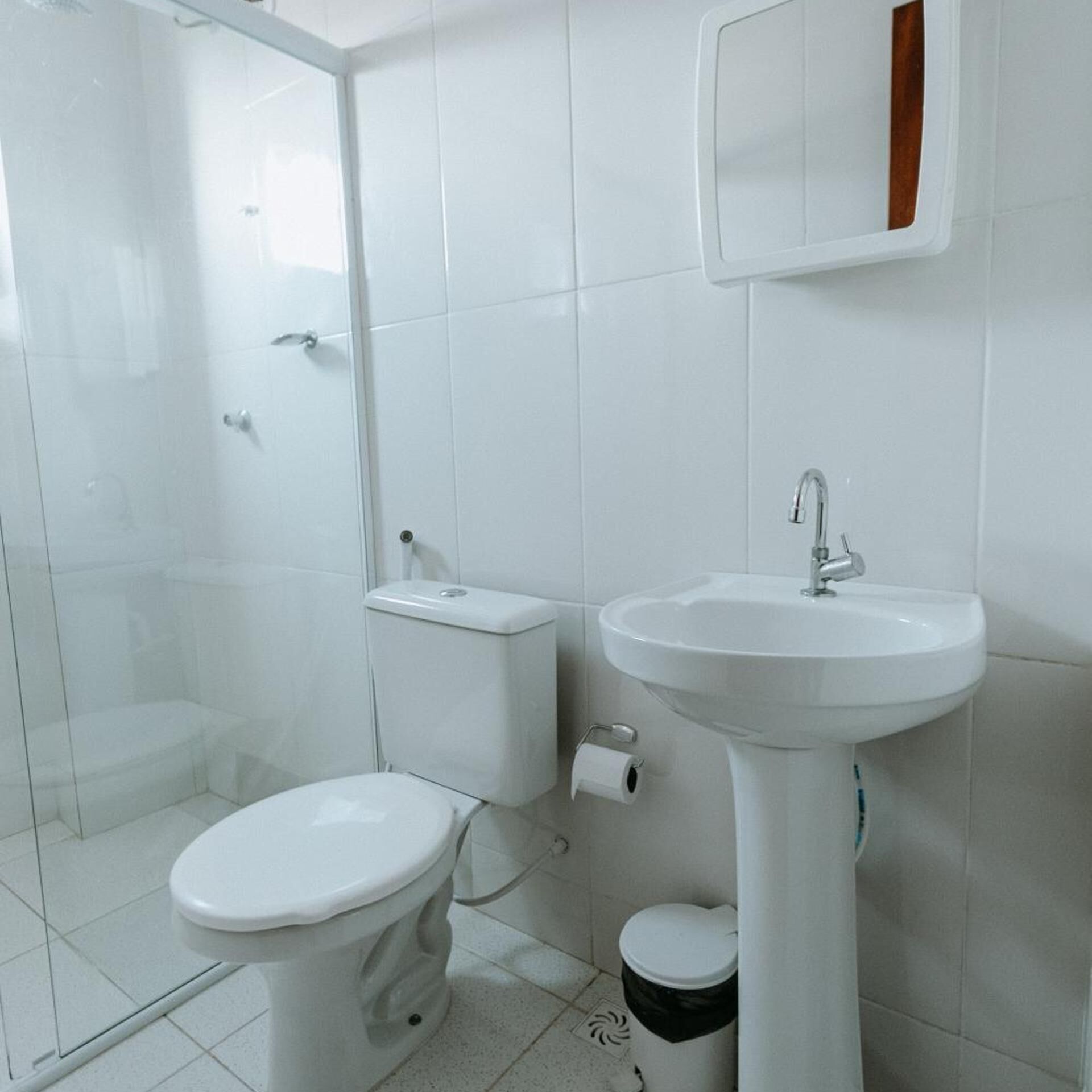 A bathroom with a toilet, a sink, and a shower enclosure.