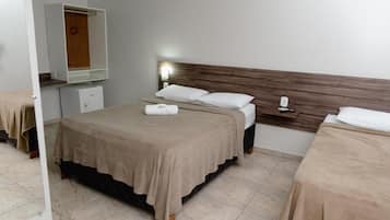 Quarto de hotel com cama, mesa de cabeceira e espelho.